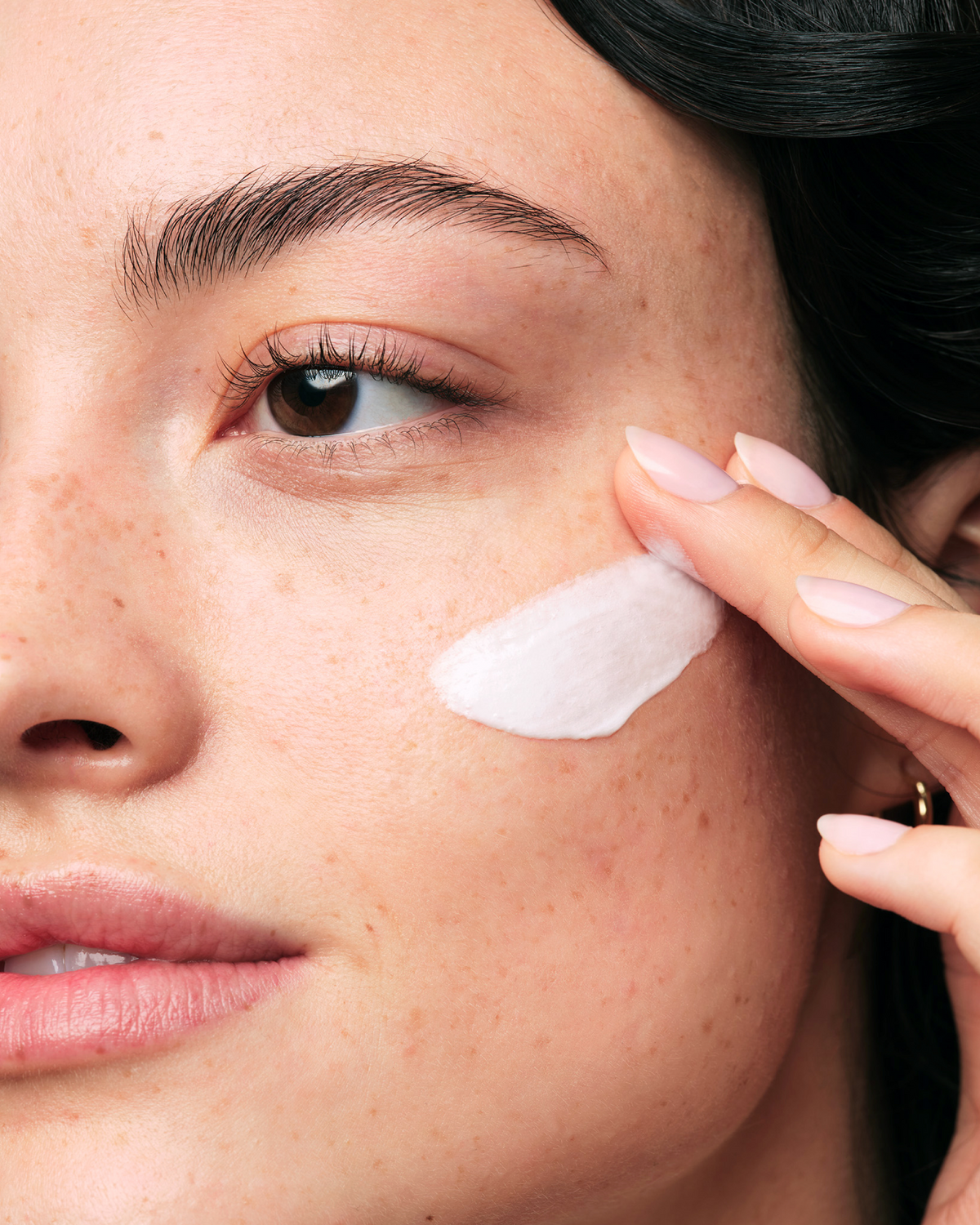 Close-up of a person applying cream to their face