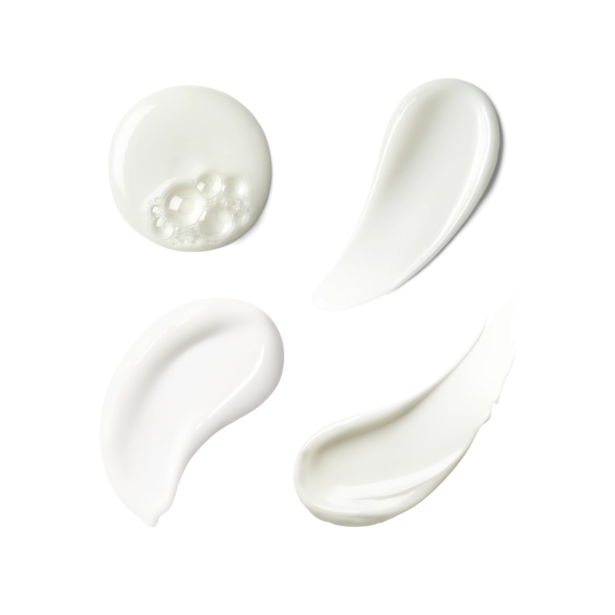 Four swatches of thick, creamy white cosmetic product, including one with visible bubbles, arranged on a plain white background.