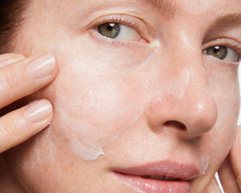 Woman applying Skinfix serum looking into camera
