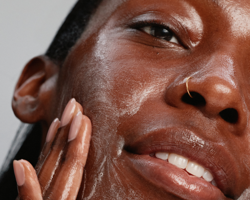 Woman applying Skinfix cleanser looking into camera